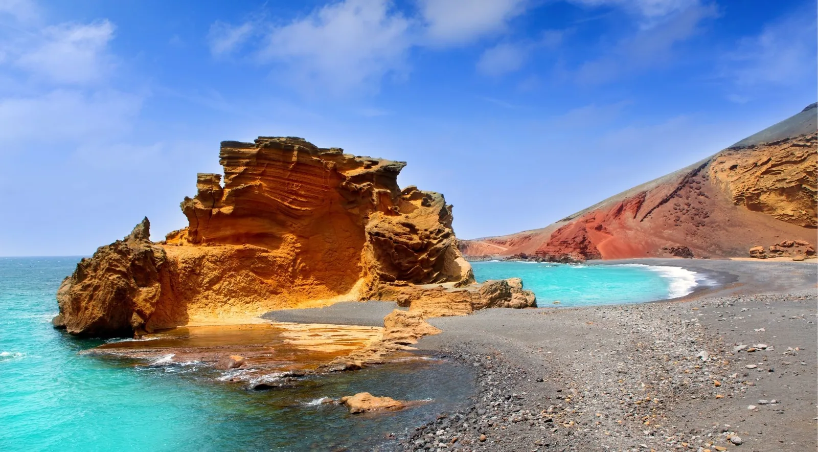Orange tuff rock formation and turquoise water beside the black sand beach at El Golfo, Lanzarote
