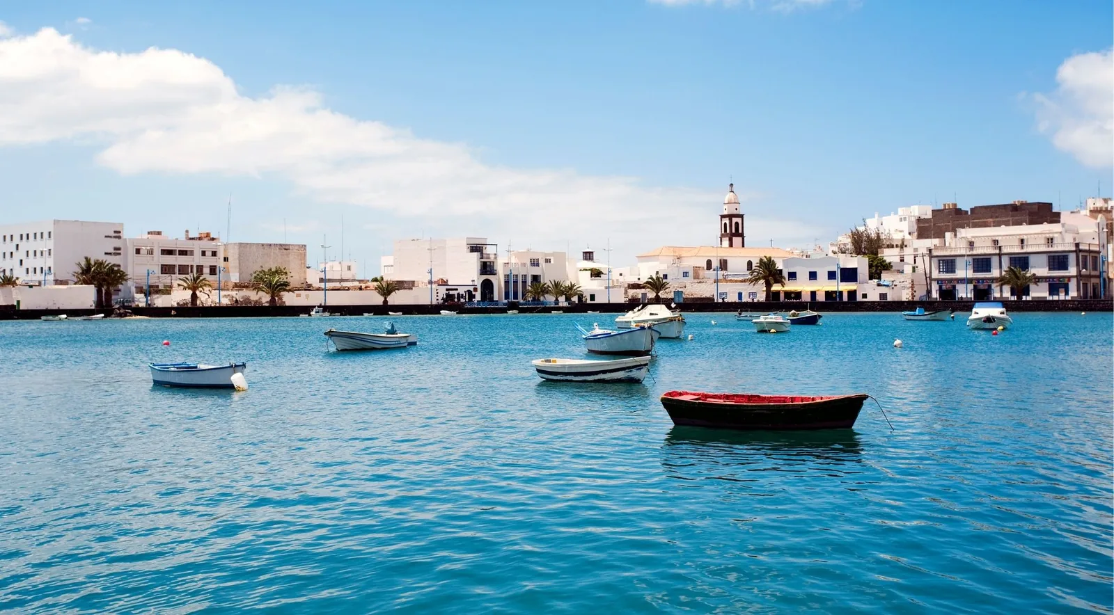 Rowing boats at anchor on the turquoise Charco de San Ginés lagoon in Arrecife under a blue sky