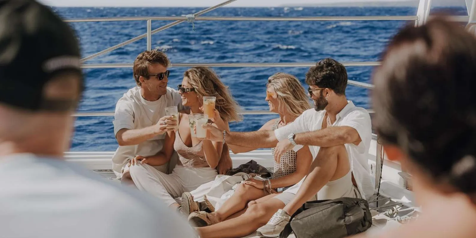 Passengers toasting with drinks on the open deck of the sunset catamaran