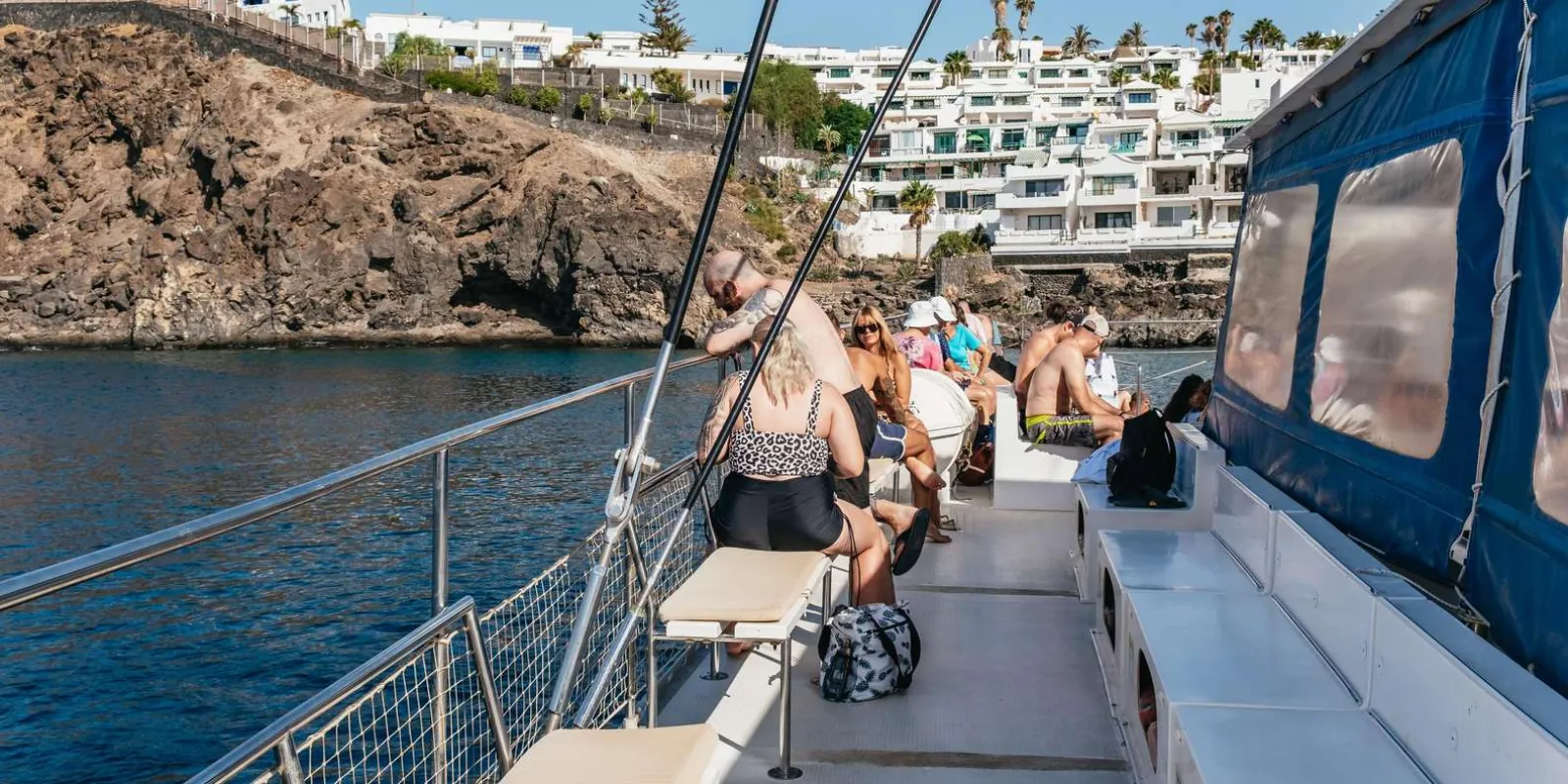 The catamaran's shaded deck at anchor below the cliffs and white villas of the coast