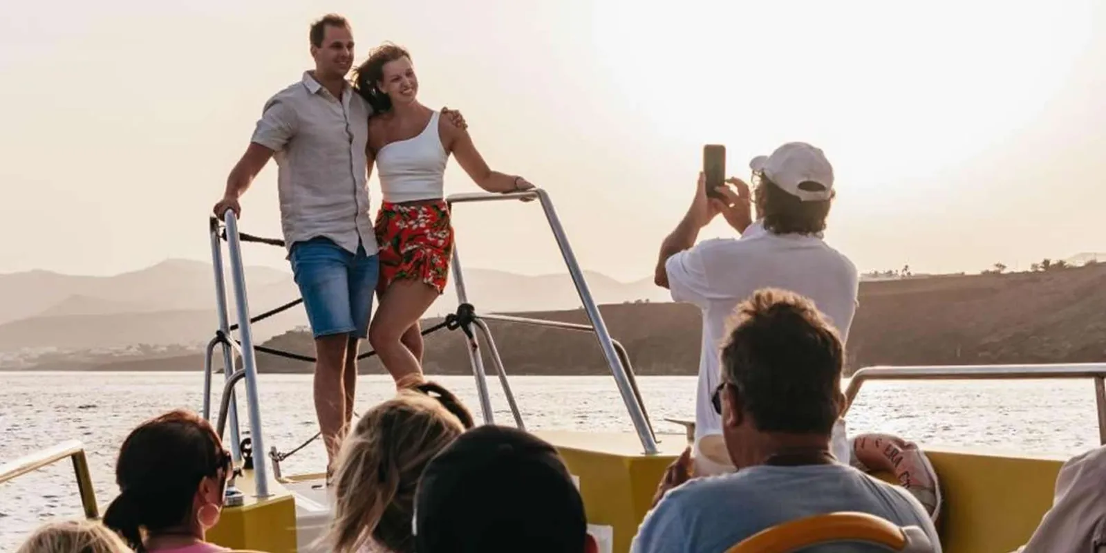 Passengers on the open deck of the fast boat watching the Lanzarote coastline